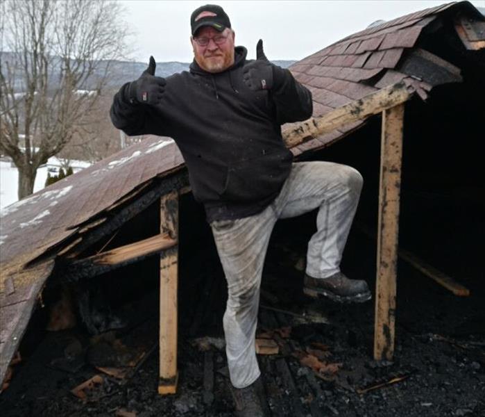 Our employee is pictured beside a fire damaged roof, getting ready to put trusses on it.