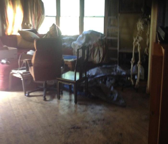 Dirty smoke residues and damaged furniture in the living room of a home.
