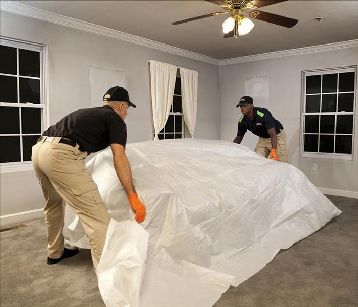 SERVPRO professionals removing a couch from a fire-damaged living room to start the restoration process.